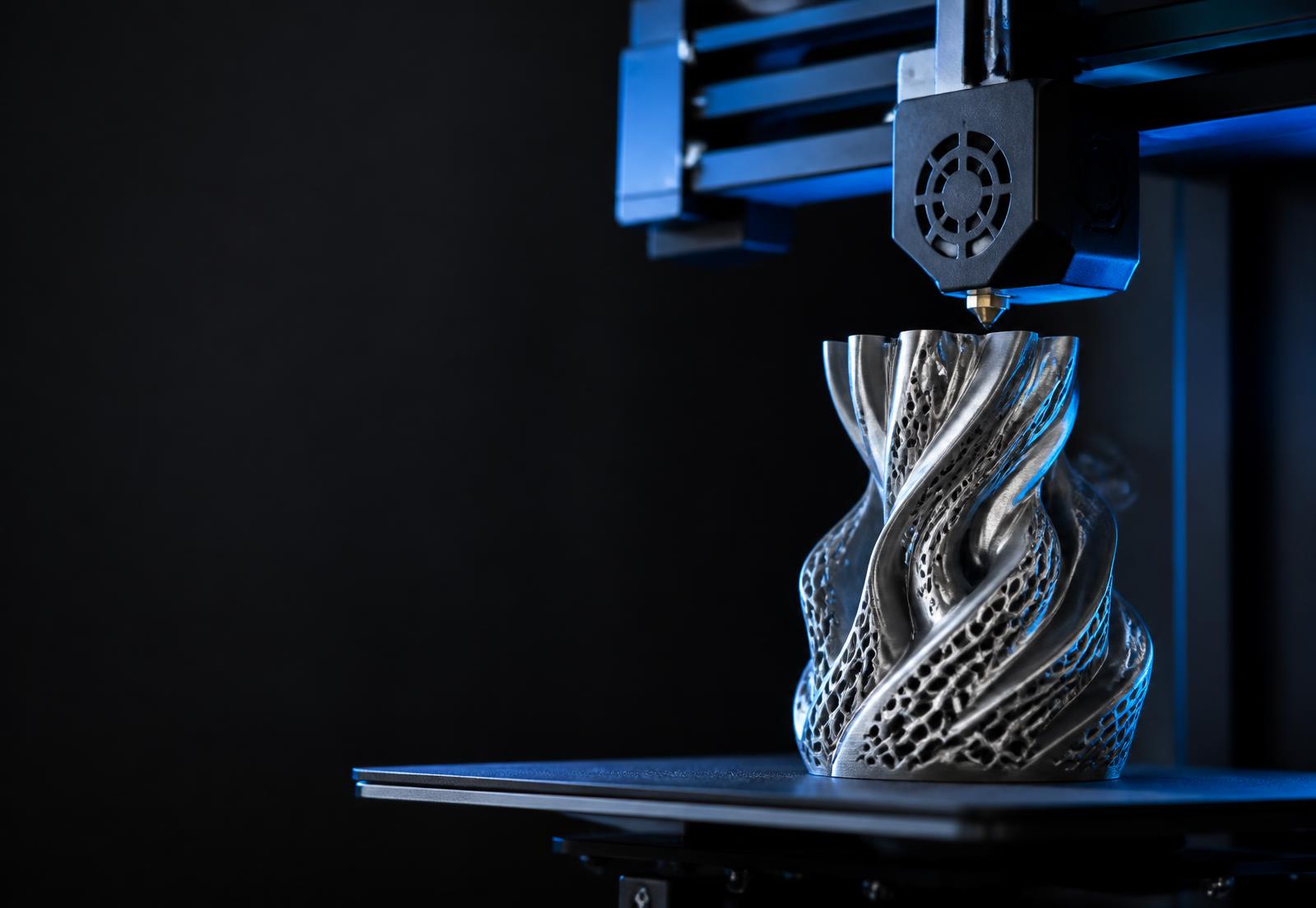 A 3D printer building an intricate sculptural object in a professional workshop